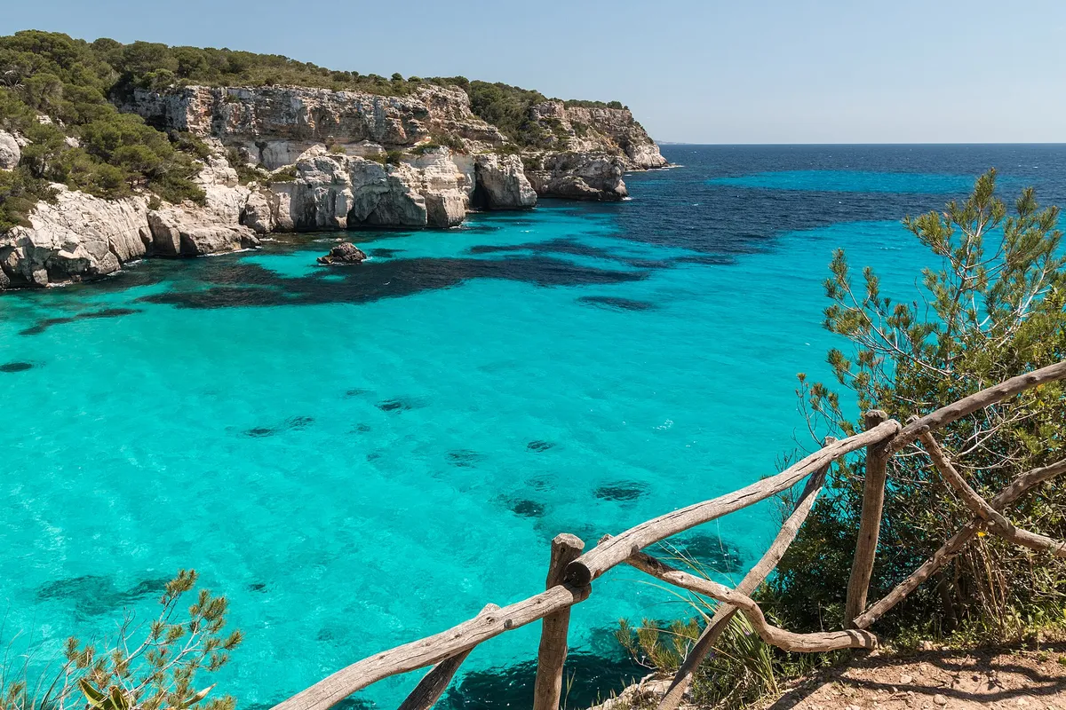 The white beach and turquoise water of Cala Macarella in Menorca, a cove both the boat half-days and the coast path reach
