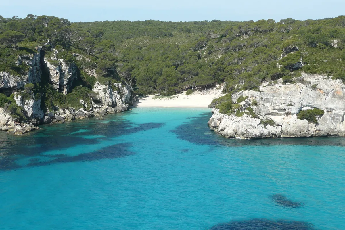 Cala Macarelleta, the smaller neighbour beach of Macarella in Menorca, set between white rocky headlands