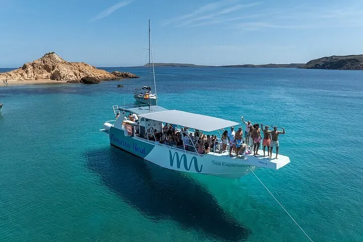 Boat anchored off a wild red-sand cove on the northern coast of Menorca inside the Fornells marine reserve