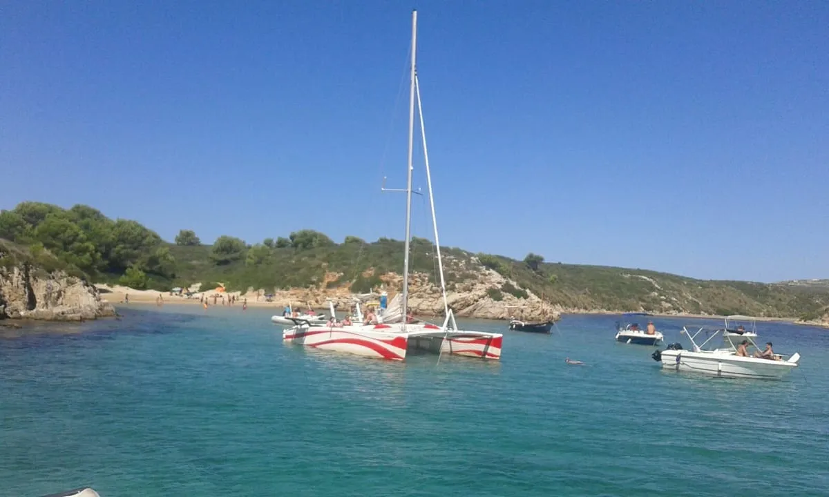 Travellers snorkelling in clear water beside a catamaran on a half-day Fornells catamaran trip with snorkelling in Menorca
